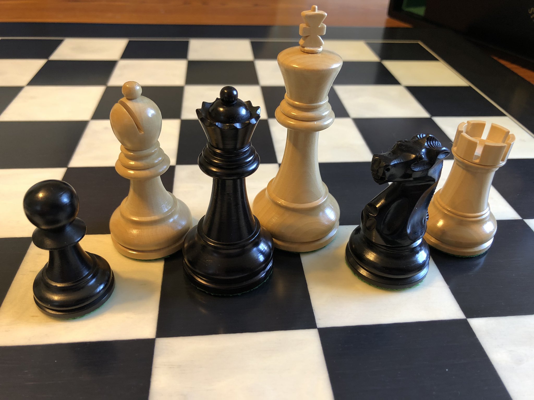 Close-up of a black pawn, queen, and knight, and a white
              bishop, king, and rook.