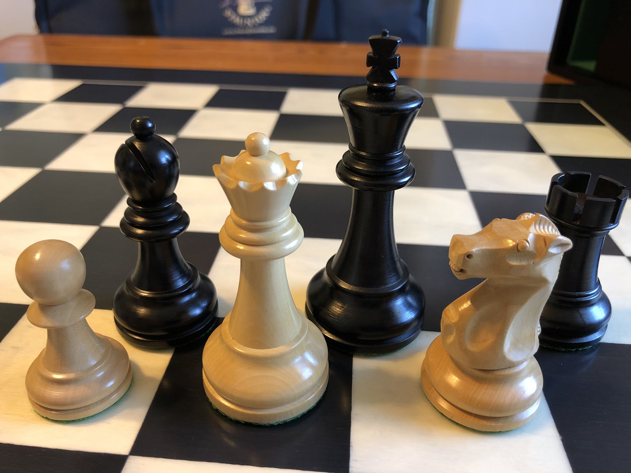 Close-up of a white pawn, queen, and knight, and a black
              bishop, king, and rook.